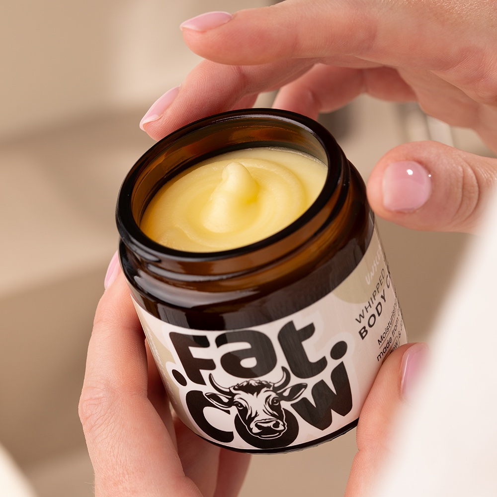 Hands opening a jar of Fat Cow whipped tallow body cream